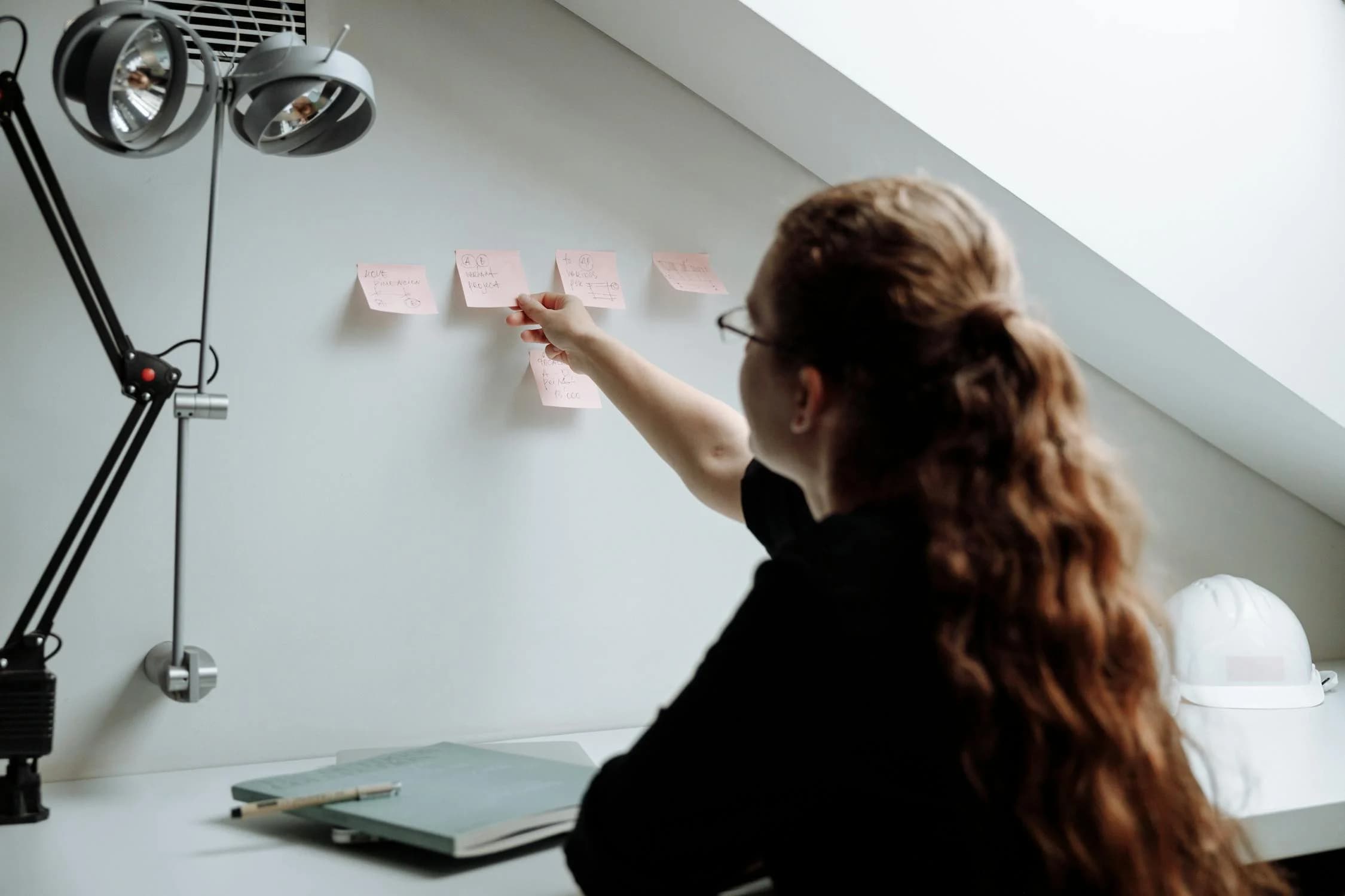 A woman sticking post-it notes on a wall